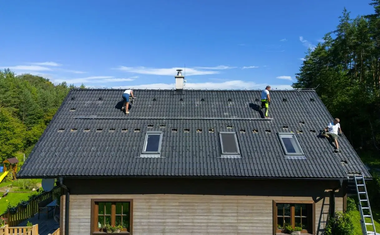 An aerial view of the house's roof with roofers working on roof structures.