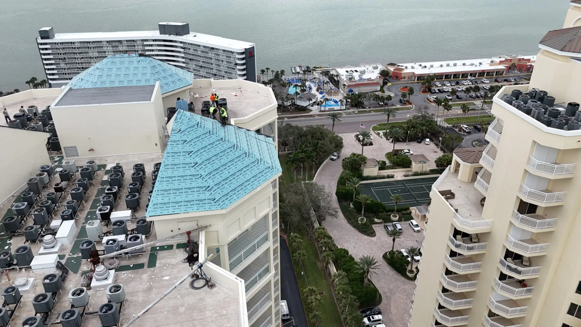 Aerial view of high rise apartments with teal colored roofs in the process of being installed.