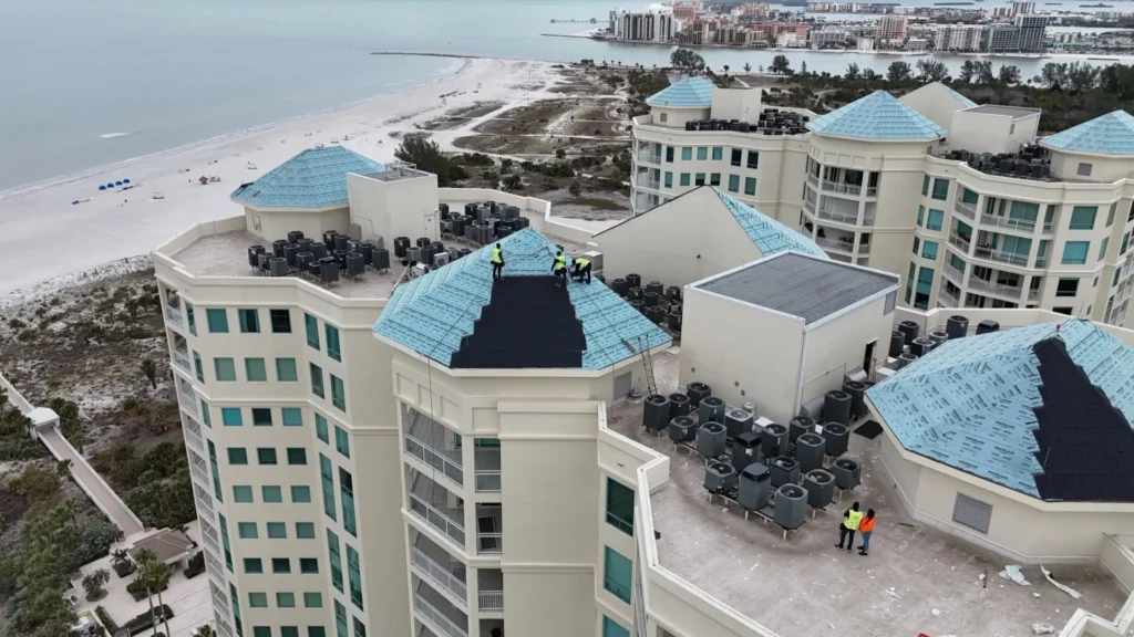 Aerial view of high rise apartments with teal colored roofs in the process of being installed.