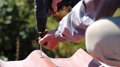 Close-up of a man fastening a screw into the roof surface.