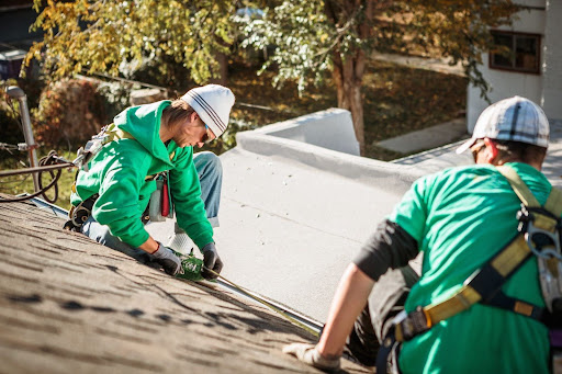 Roofing crew taking measurements on a residential roof before repairs.