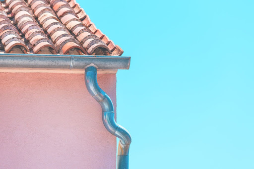 Curved rain gutter on rustic Mediterranean-style house exterior.