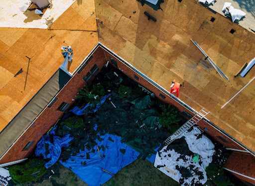 A worker performing roofing repairs and installing new shingles on a residential roof.