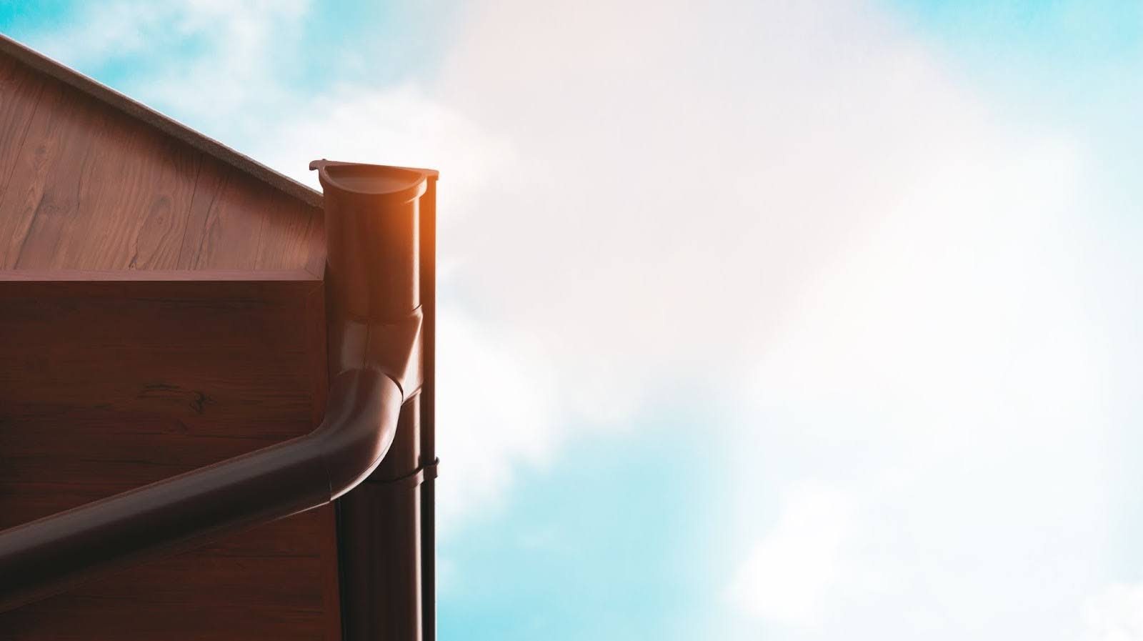 Well-aligned rain gutter contrasting with sunny, cloud-filled background