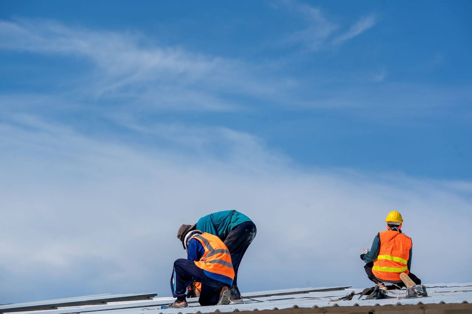 Roofing contractors installing metal profile panels on a rooftop