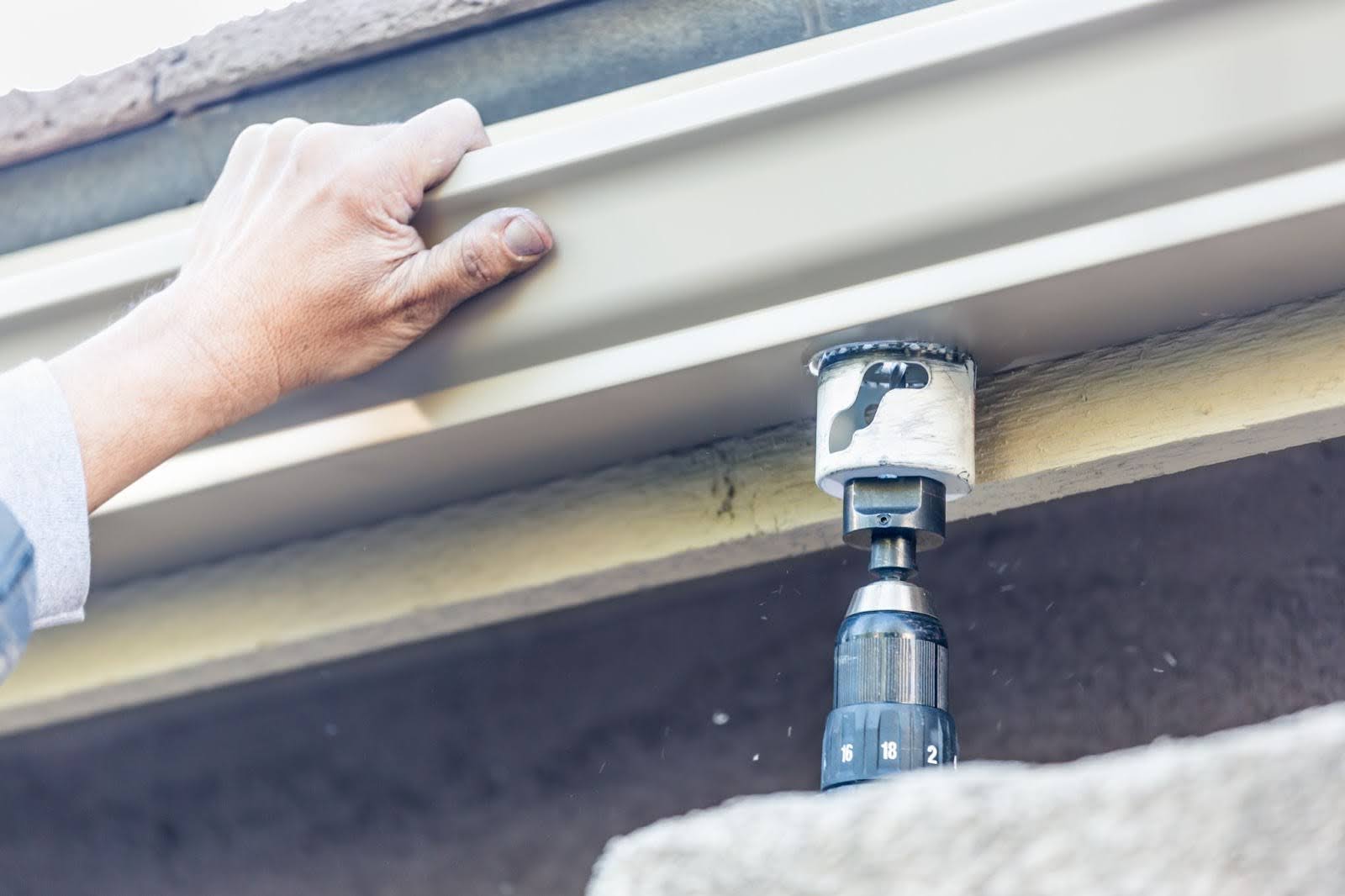 Detailed view of an aluminum gutter being fastened to the fascia by a contractor.