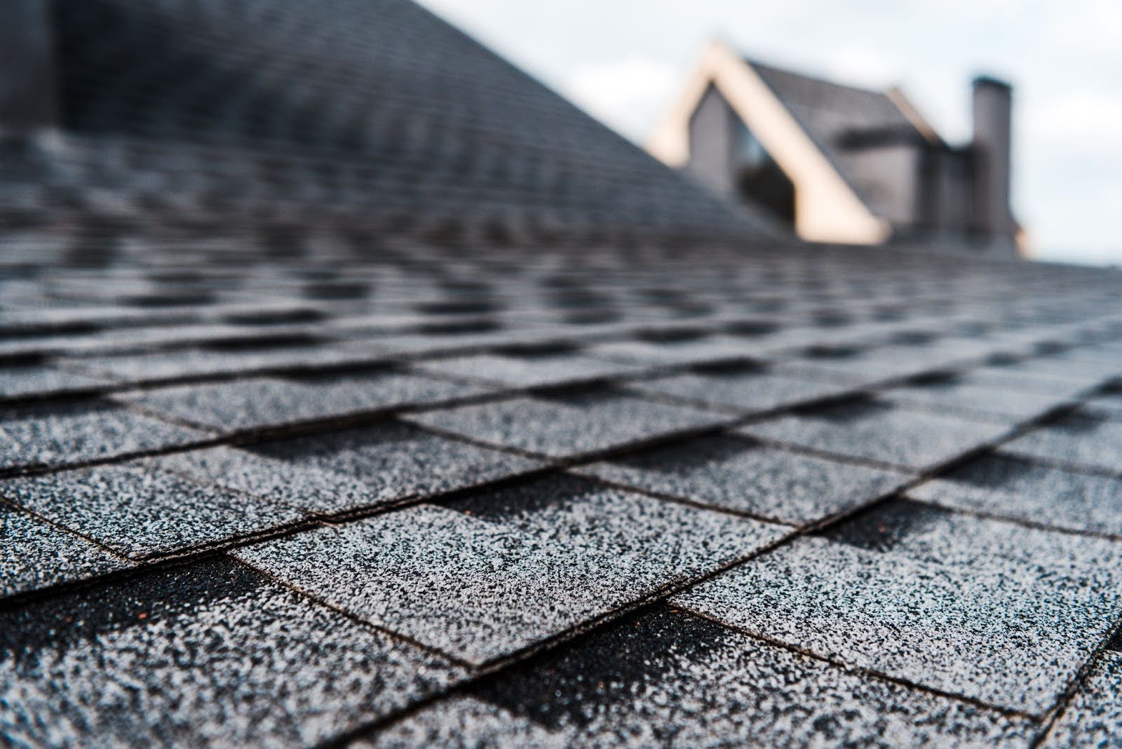 Close-up of grey roofing shingles on a sloped building roof, shown in sharp detail.