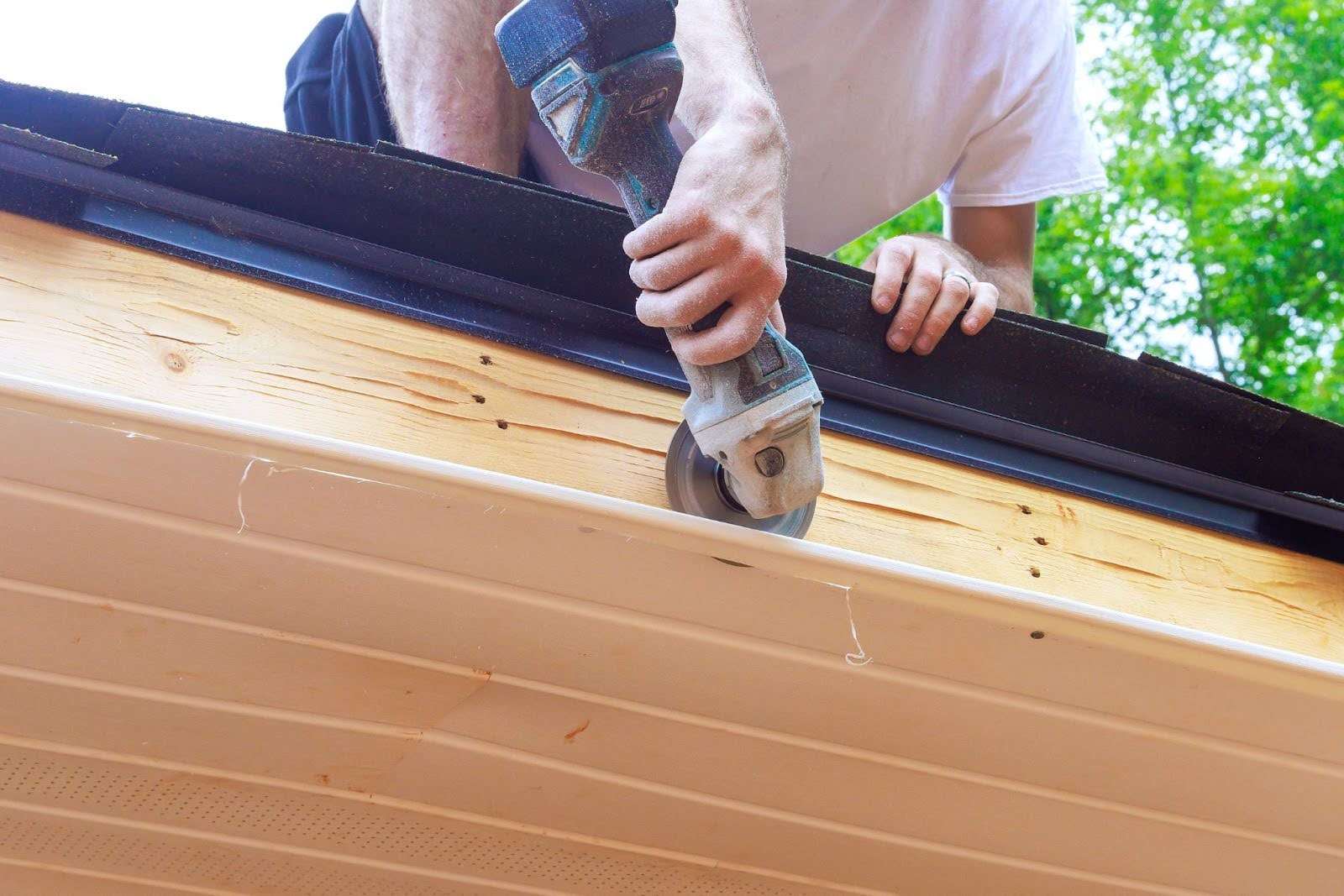 A worker cuts the vinyl soffit panels to the required size during installation.