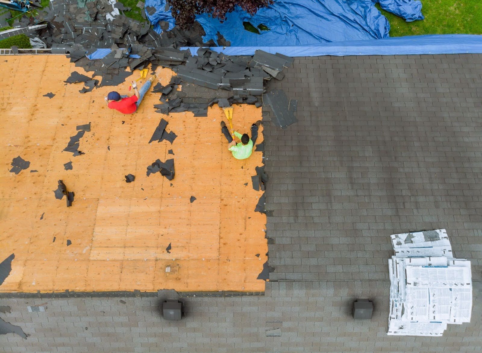 Roof replacement is in progress on the apartment complex, showing the removal of old shingles.