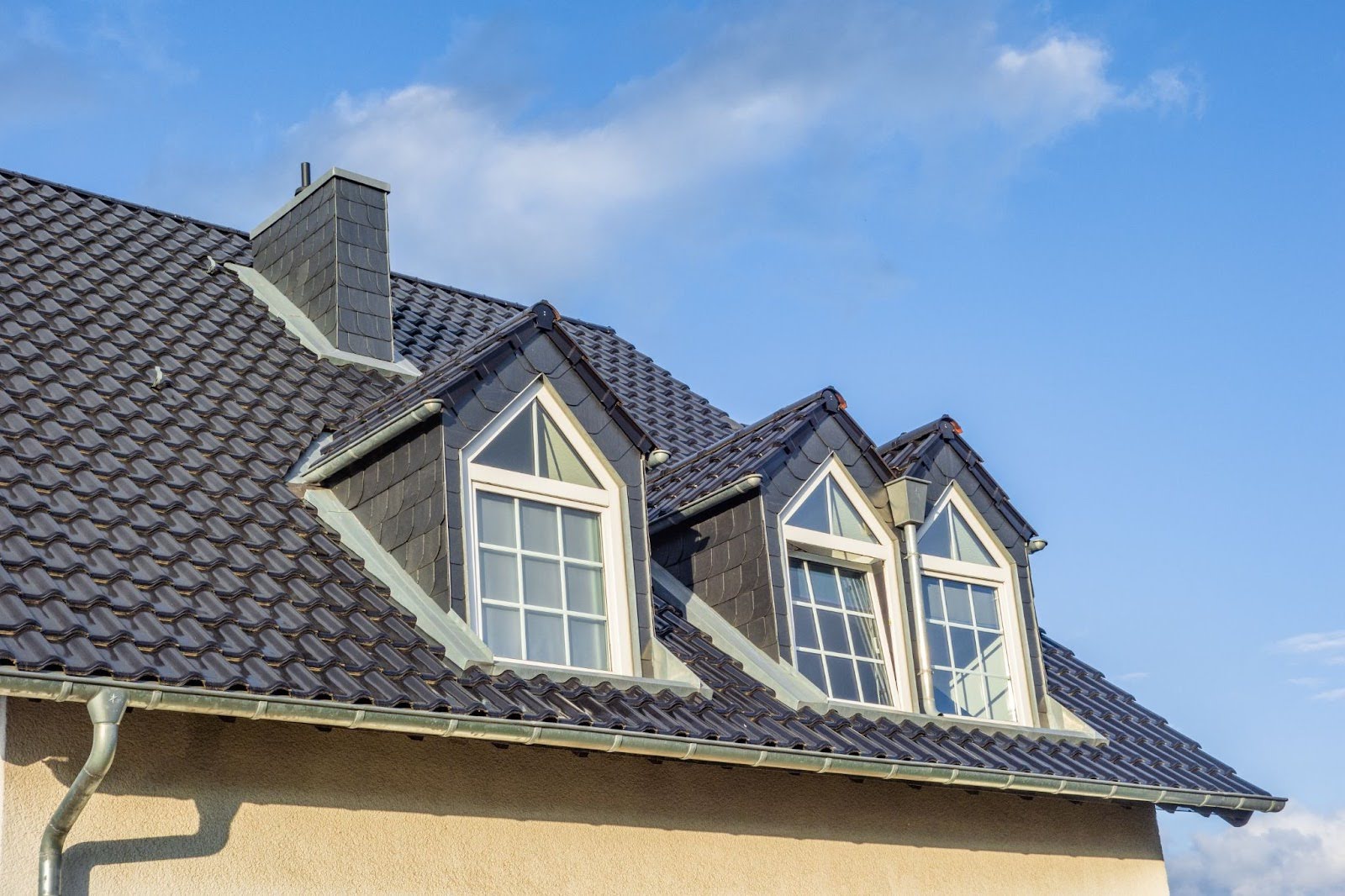 A home with a newly installed roof and dormers with a clear sky background.