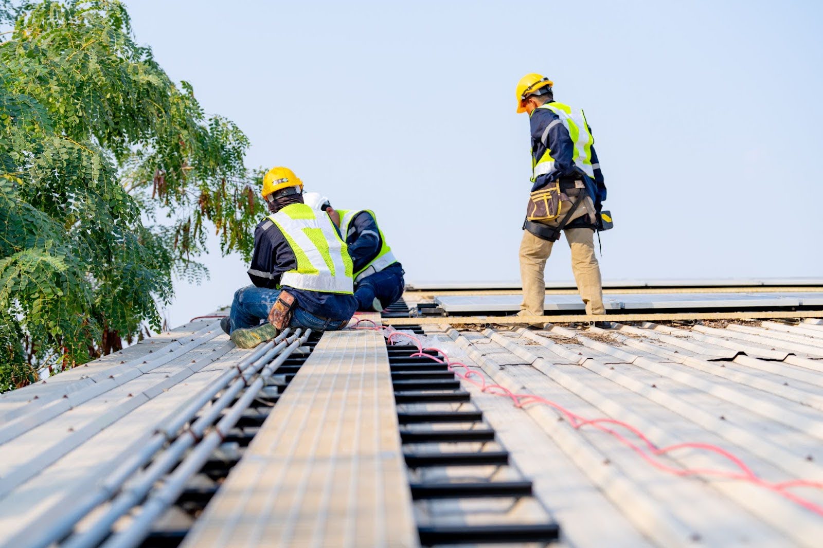 Three construction workers are on a roof.