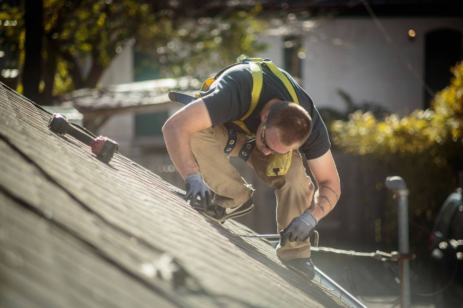 A worker is on a roof installing shingles on a roof.