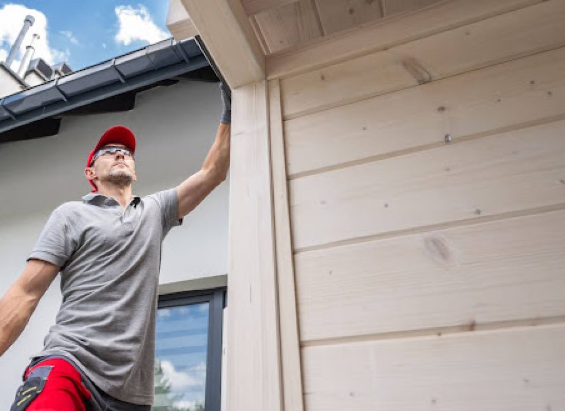 A worker inspects the exterior of a house before installing new gutters.