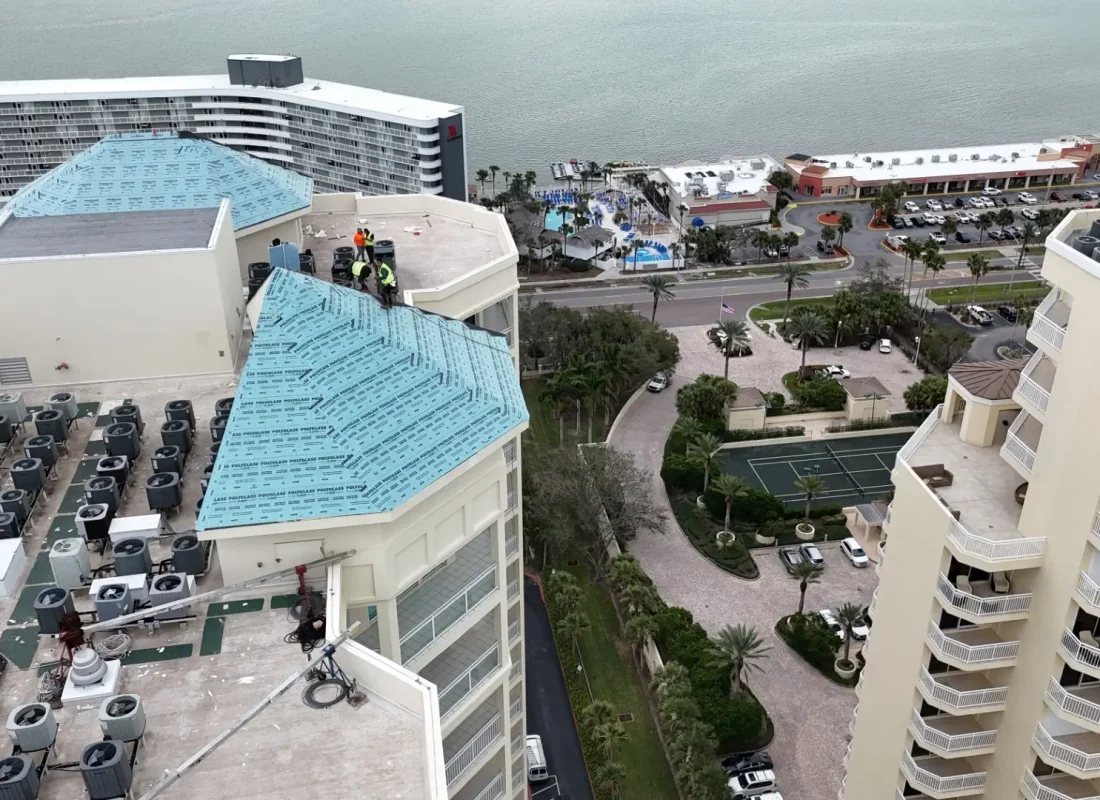 Aerial view of high rise apartments with teal colored roofs in the process of being installed.