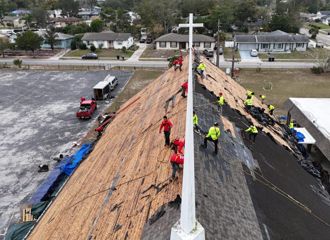 Large roofing crew removing old shingles from a church roof by Febres Roofing